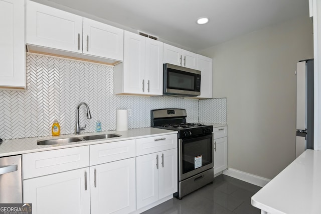 kitchen with white cabinetry, stainless steel appliances, sink, and decorative backsplash