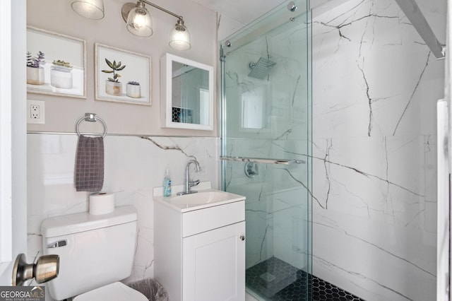 bathroom featuring vanity, toilet, a shower with door, and tile walls