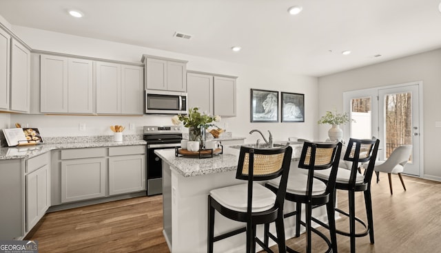 313 Sound Cir Unit 140, Stockbridge, GA 30281 - kitchen featuring appliances with stainless steel finishes, a breakfast bar area, wood finished floors, gray cabinetry, and recessed lighting