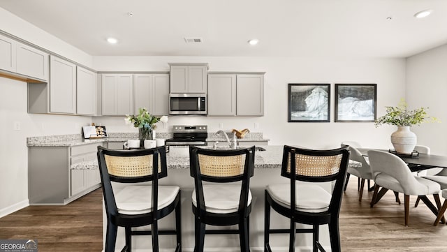 313 Sound Cir Unit 140, Stockbridge, GA 30281 - kitchen featuring appliances with stainless steel finishes, light stone countertops, gray cabinetry, a center island with sink, and recessed lighting