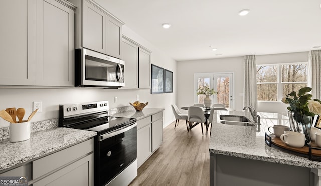 313 Sound Cir Unit 140, Stockbridge, GA 30281 - kitchen featuring appliances with stainless steel finishes, a sink, light wood-style flooring, light stone countertops, and gray cabinets
