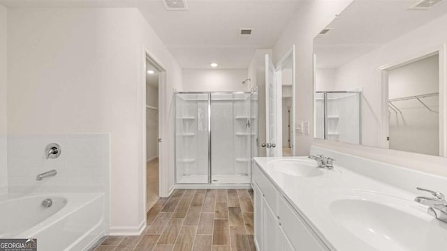 313 Sound Cir Unit 140, Stockbridge, GA 30281 - bathroom with a shower stall, wood tiled floors, a walk in closet, a bath, and double vanity