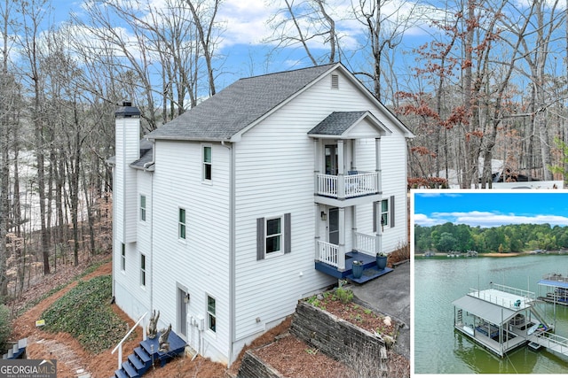 view of home's exterior featuring a water view, a balcony, and a boat dock