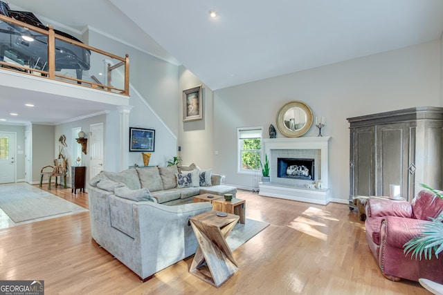 living room with light wood-type flooring, high vaulted ceiling, and ornamental molding