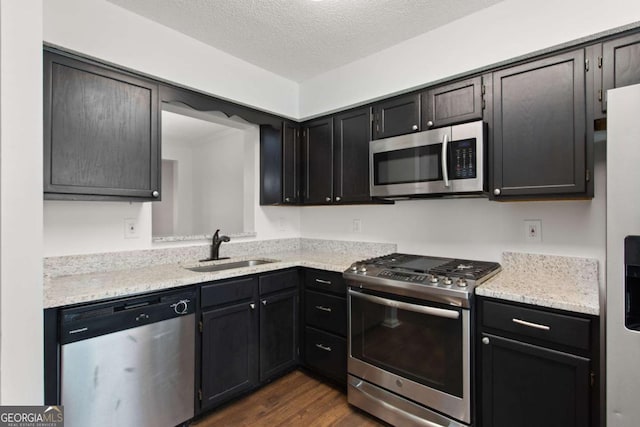 kitchen featuring sink, dark wood-type flooring, stainless steel appliances, and a textured ceiling