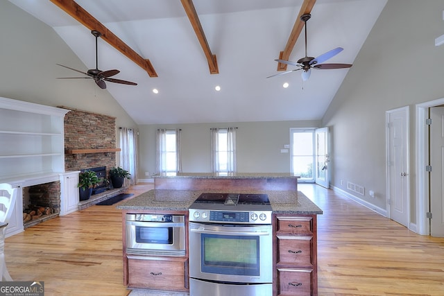 kitchen featuring stainless steel appliances, light hardwood / wood-style flooring, a fireplace, and beamed ceiling