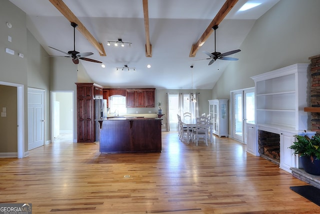 kitchen featuring hanging light fixtures, a stone fireplace, beam ceiling, and light hardwood / wood-style floors