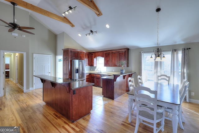 kitchen featuring appliances with stainless steel finishes, a kitchen breakfast bar, decorative light fixtures, and light wood-type flooring