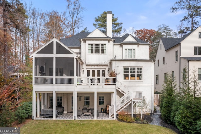 rear view of property with a yard, a sunroom, and a patio