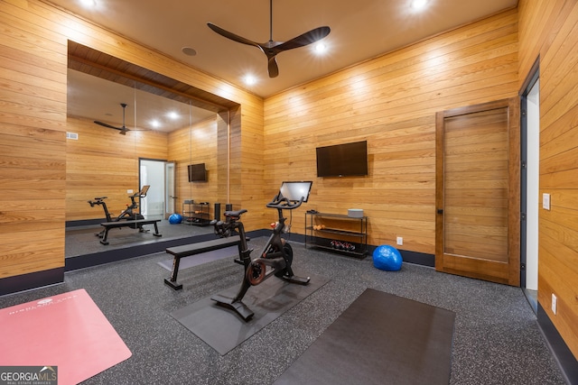 exercise room featuring ceiling fan and wood walls