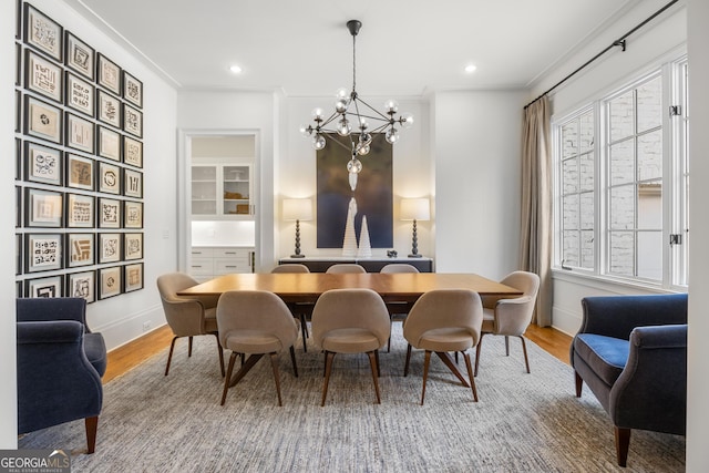 dining area featuring wood-type flooring, an inviting chandelier, and crown molding