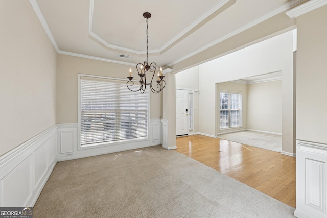 spare room with crown molding, a tray ceiling, light hardwood / wood-style floors, and a notable chandelier