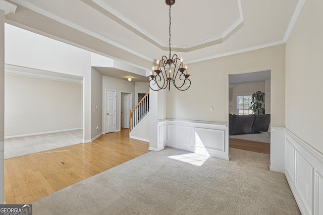 carpeted dining area featuring an inviting chandelier, ornamental molding, and a raised ceiling