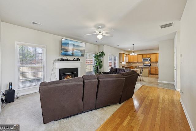 living room featuring ceiling fan with notable chandelier and a wealth of natural light