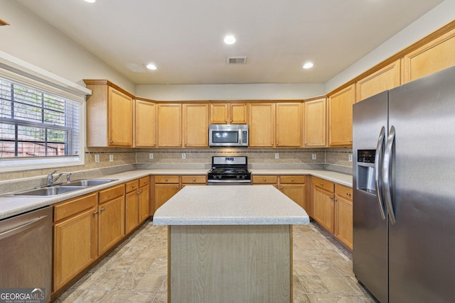 kitchen featuring tasteful backsplash, appliances with stainless steel finishes, sink, and a kitchen island