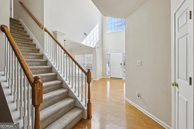 foyer entrance with a towering ceiling and light hardwood / wood-style flooring