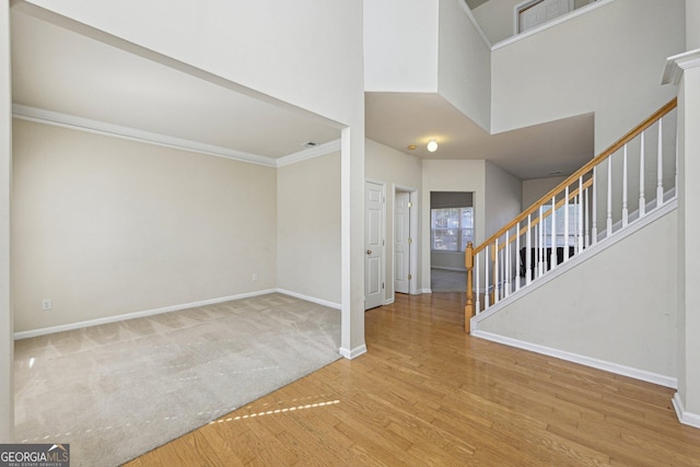 entrance foyer with hardwood / wood-style flooring, ornamental molding, and a towering ceiling