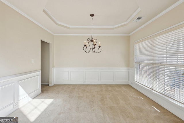 unfurnished room featuring light colored carpet, ornamental molding, a raised ceiling, and a notable chandelier