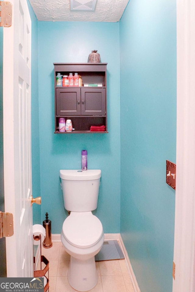 bathroom featuring tile patterned floors, toilet, and a textured ceiling