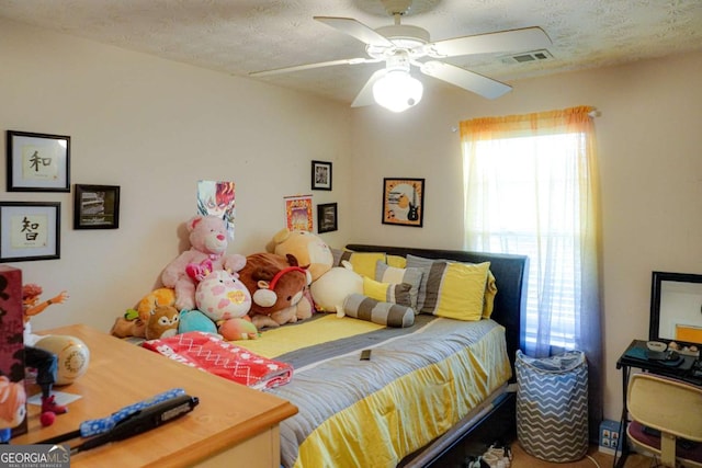 bedroom with ceiling fan and a textured ceiling