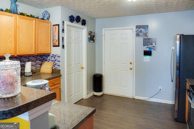 kitchen with stainless steel refrigerator, tasteful backsplash, kitchen peninsula, dark wood-type flooring, and a textured ceiling