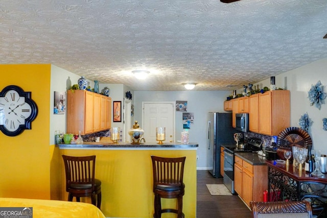 kitchen featuring dark wood-type flooring, a kitchen breakfast bar, kitchen peninsula, and appliances with stainless steel finishes