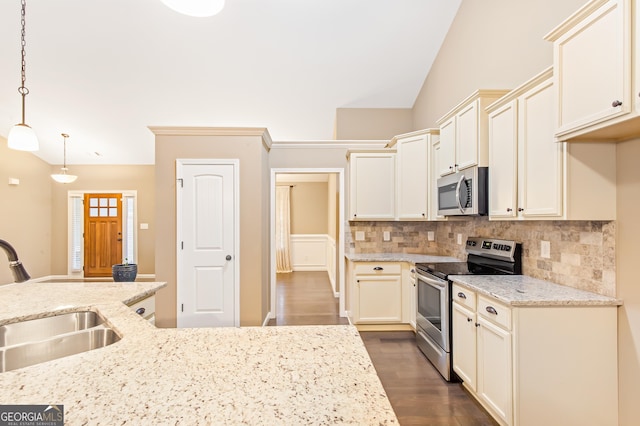 kitchen with sink, stainless steel appliances, light stone counters, decorative light fixtures, and vaulted ceiling