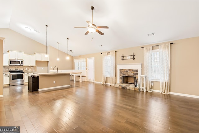 living room featuring sink, high vaulted ceiling, dark hardwood / wood-style floors, ceiling fan, and a fireplace