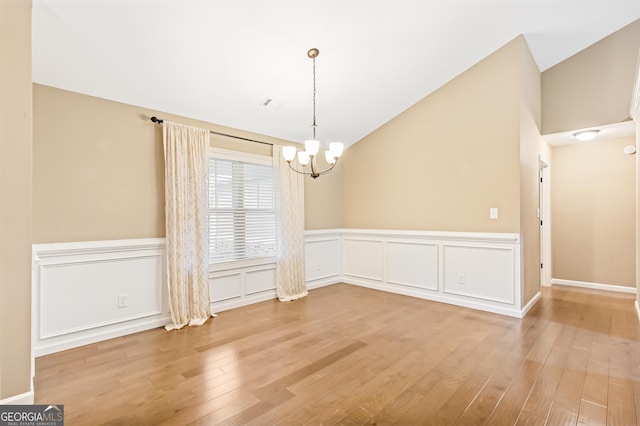 unfurnished dining area with lofted ceiling, a chandelier, and wood-type flooring