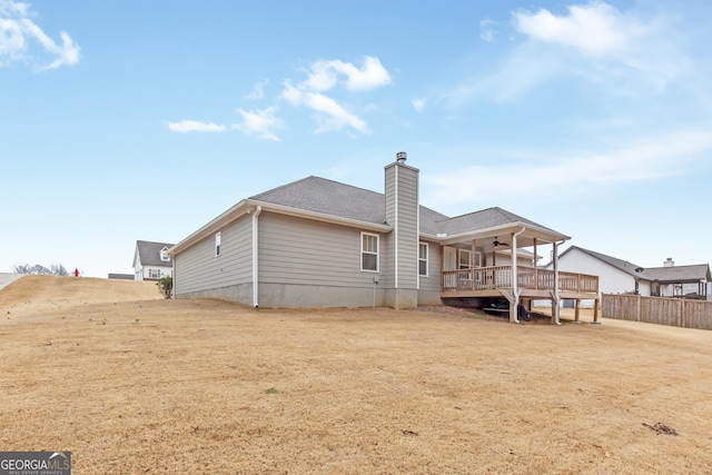 back of property with a wooden deck, ceiling fan, and a lawn