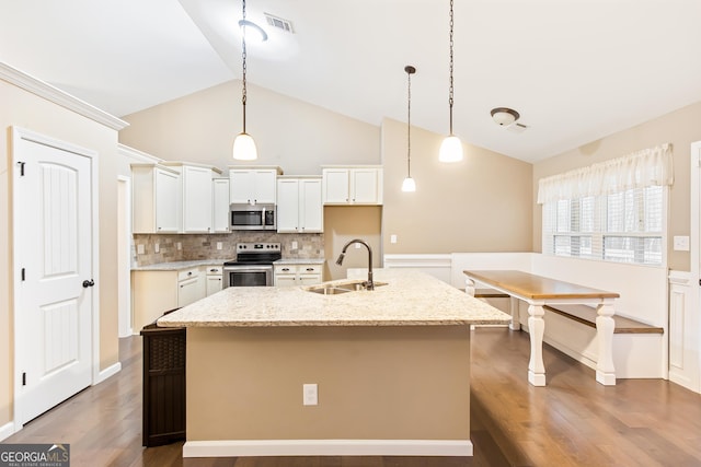 kitchen with appliances with stainless steel finishes, pendant lighting, sink, white cabinets, and a center island with sink