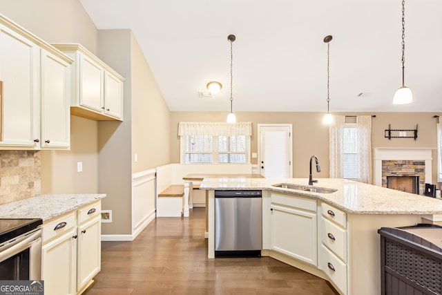 kitchen featuring sink, stainless steel appliances, a center island with sink, decorative light fixtures, and cream cabinetry