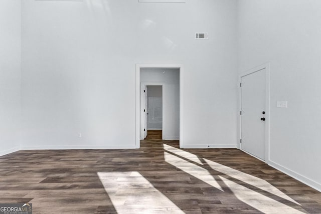 spare room with dark wood-type flooring and a high ceiling