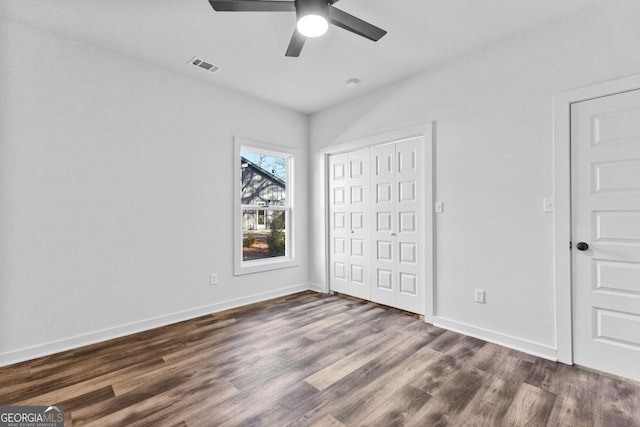 unfurnished bedroom featuring ceiling fan, dark hardwood / wood-style floors, and a closet