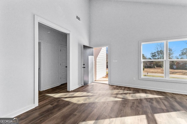 interior space featuring a towering ceiling and dark hardwood / wood-style flooring