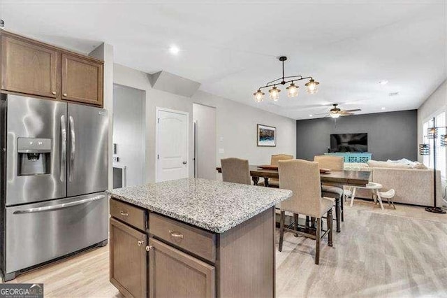 kitchen featuring pendant lighting, stainless steel fridge, a center island, ceiling fan, and light hardwood / wood-style flooring