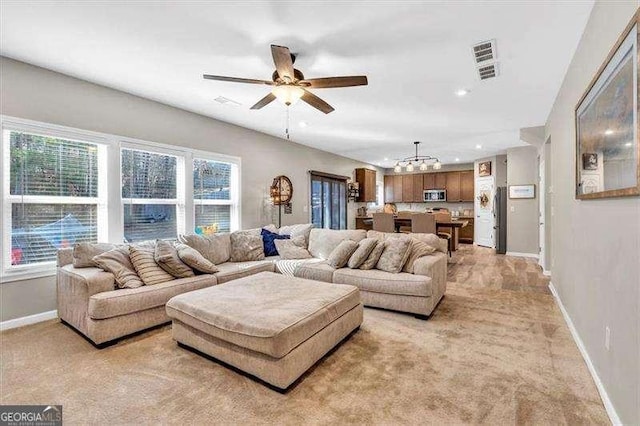 carpeted living room featuring ceiling fan with notable chandelier