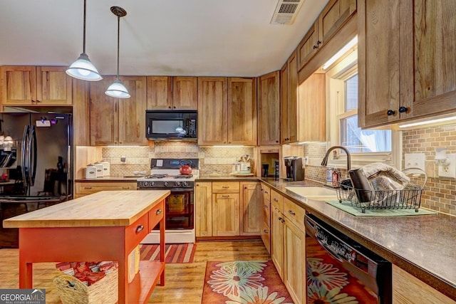 kitchen with a kitchen island, butcher block counters, sink, black appliances, and light wood-type flooring