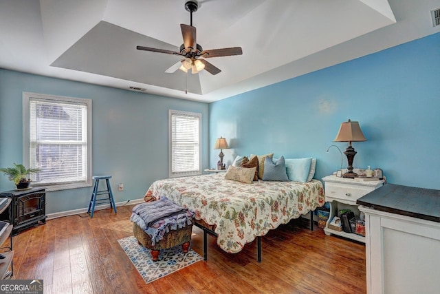 bedroom with a raised ceiling, hardwood / wood-style floors, and ceiling fan