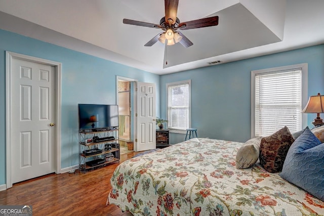 bedroom featuring ceiling fan, a tray ceiling, and hardwood / wood-style floors