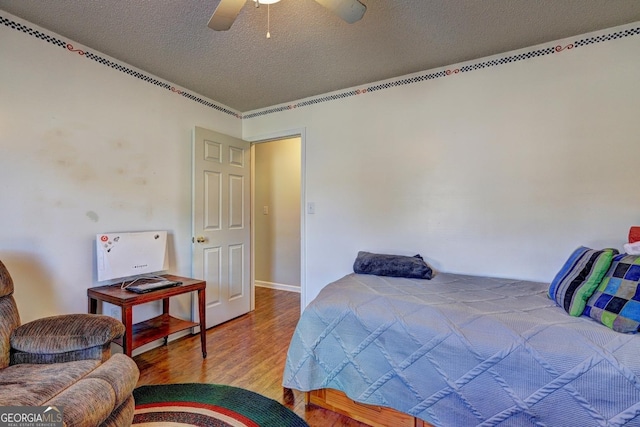 bedroom with ceiling fan, hardwood / wood-style floors, and a textured ceiling