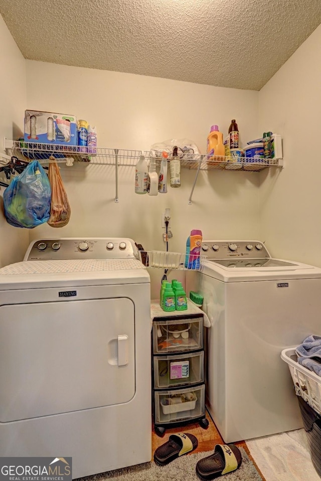 laundry area with separate washer and dryer and a textured ceiling