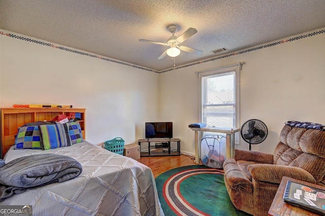 bedroom featuring ceiling fan, wood-type flooring, and a textured ceiling