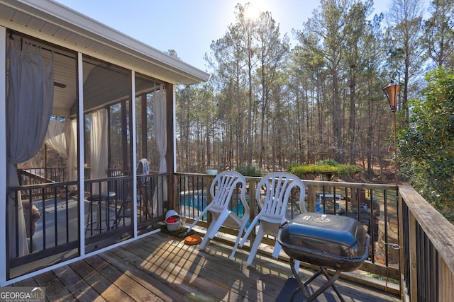 wooden deck with a grill and a sunroom