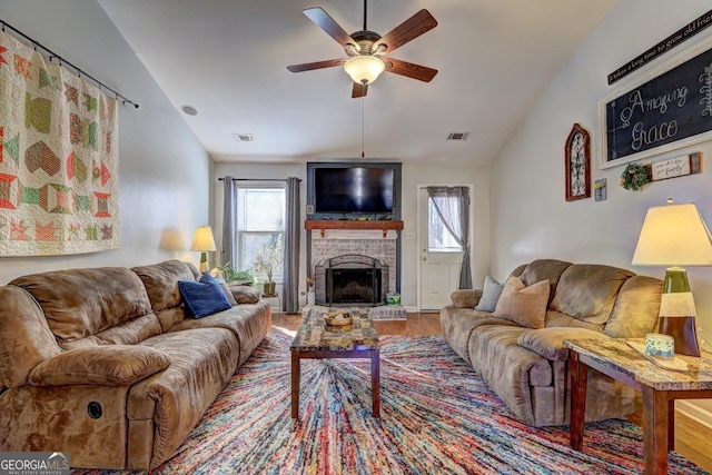 living room with ceiling fan, wood-type flooring, a fireplace, and vaulted ceiling