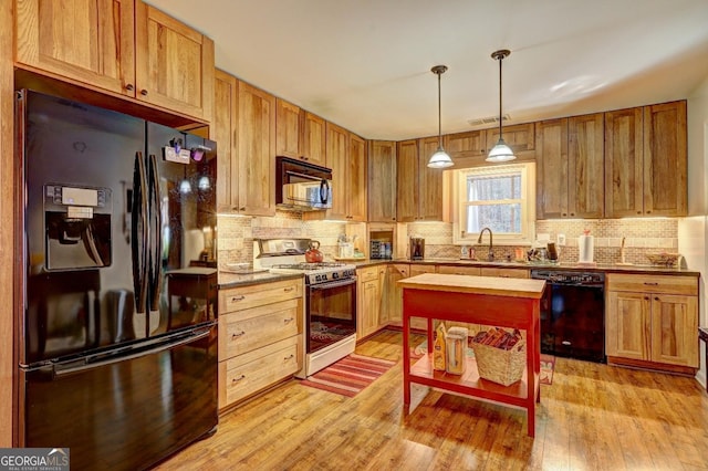 kitchen with light hardwood / wood-style floors, hanging light fixtures, black appliances, and sink