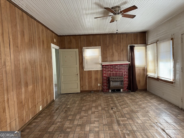 unfurnished living room featuring heating unit, a fireplace, wooden walls, and ceiling fan