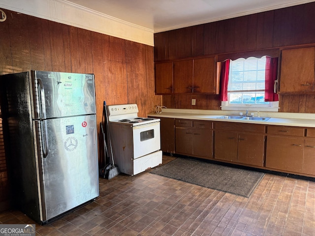 kitchen with sink, wooden walls, white electric stove, and stainless steel refrigerator