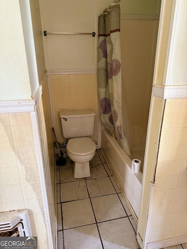 bathroom featuring tile patterned flooring, tile walls, shower / tub combo with curtain, and toilet