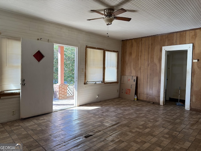 foyer featuring wooden walls and ceiling fan